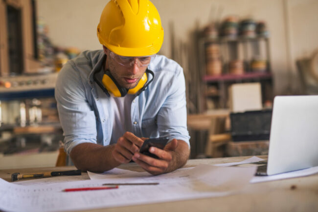 Arbetsorder med TimeApp (foto: Adobe Stock) En arbetar som står med sin telefon