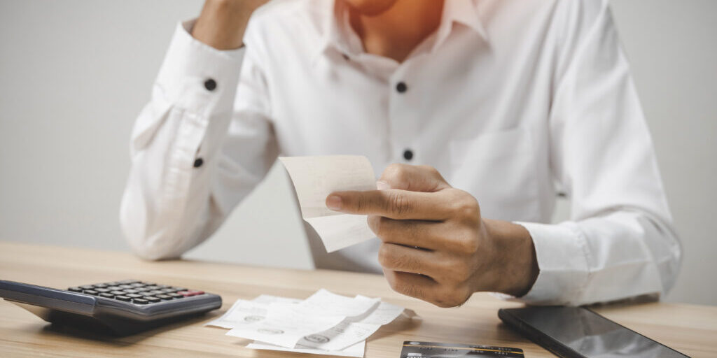 stressed young male upset and worried about credit card and fami En man som tittar på sina kvitton och räknar på sina utlägg